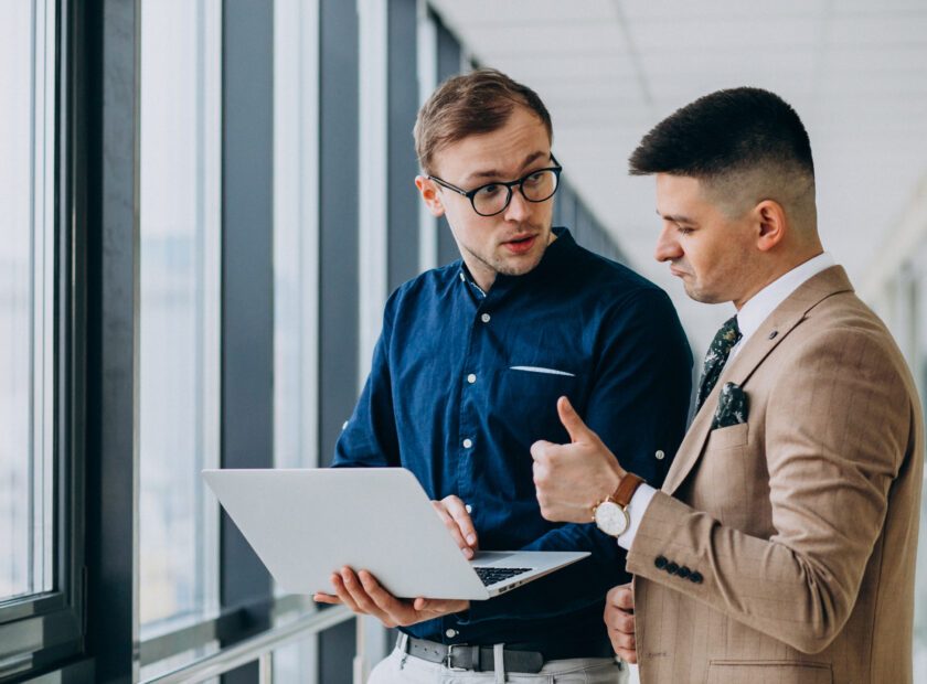 Two male colleagues at the office,standing with laptop